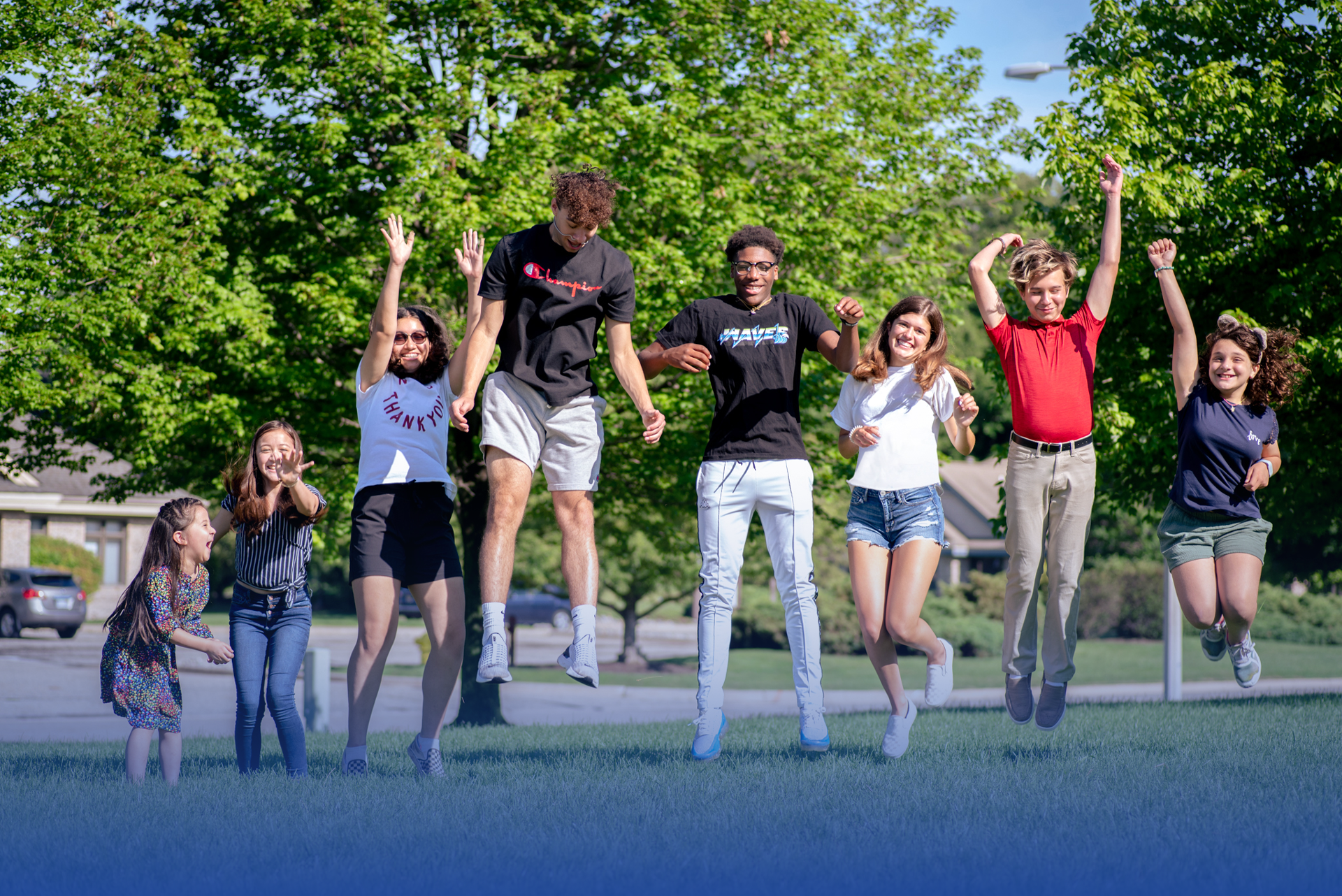 Group of kids jumping in the air outside in the summer.