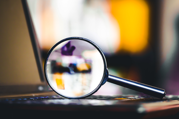 A magnifying glass atop a laptop computer.